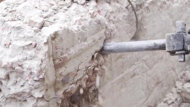 एक शक्तिशाली इलेक्ट्रिक हैमर के साथ एक कंक्रीट दीवार का विध्वंस एक तेज लगाव के साथ — स्टॉक वीडियो
