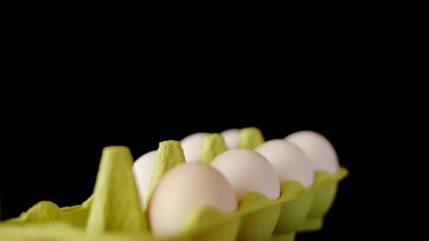 Bandeja verde con huevos de pollo blanco girando sobre fondo negro — Vídeos de Stock