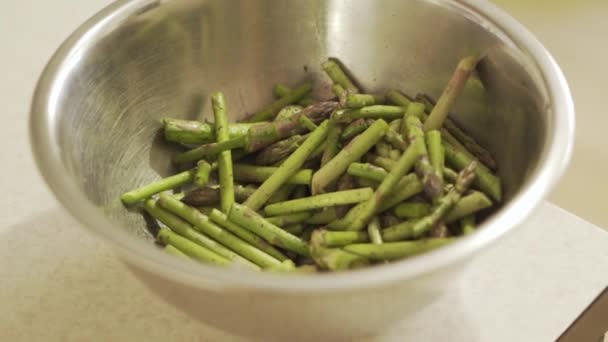 Gesnipperde stukjes groene asperges zitten in een container gemarineerd in specerijen — Stockvideo