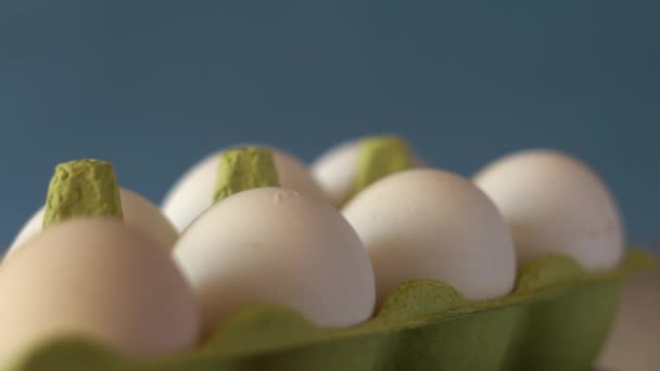 Beyaz tavuk yumurtalı yeşil karton tepsi yakın planda dönüyor. — Stok video