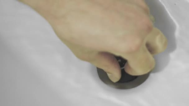 De hand trekt de rubberen stop uit de gootsteen, het water stroomt in het afvoergat — Stockvideo