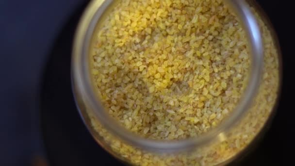 Raw couscous groats spinning in a glass jar — Stock Video