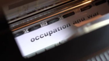 Printer carriage prints on white glossy paper the words occupation and war