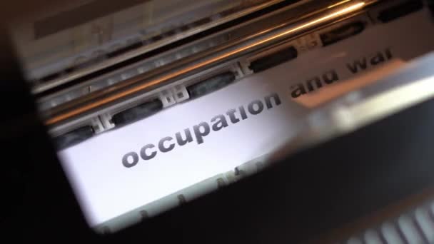 Printer carriage prints on white glossy paper the words occupation and war — Vídeo de Stock