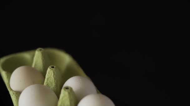 黒を背景に白い鶏の卵が渦巻く緑のトレイ — ストック動画