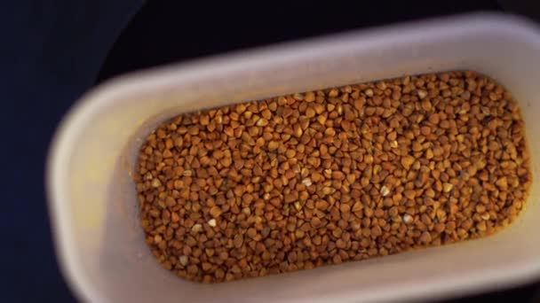 Plastic container with buckwheat is spinning close-up — Stock Video