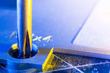 Yıldız tornavidayla küçük bir vidayı sökmek bir dizüstü bilgisayarın yakın plan görüntüsü, sarı-mavi ışıklandırma.