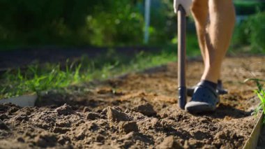 A guy cultivates the soil of a vegetable garden bed with a shovel, close-up in slow motion. High quality FullHD footage
