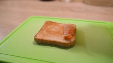 Hafif tuzlu alabalık, yeşil mutfak kesim tahtasına yakın plan beyaz ekmekli tostun üzerine yerleştirilir. Yüksek kalite 4k görüntü