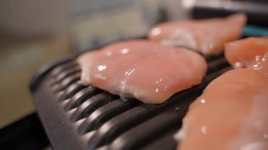 Çiğ tavuk fileto elektrikli ızgarada pişiriliyor, yakın plan. Yüksek kaliteli FullHD görüntüler