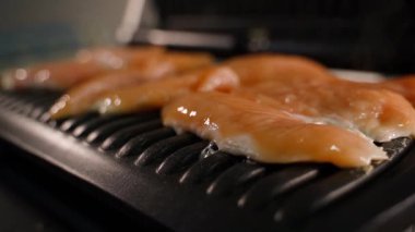 Çiğ tavuk göğsü elektrikli ızgarada kızartılıyor, yakın çekim, pürüzsüz kamera hareketi. Yüksek kaliteli FullHD görüntüler