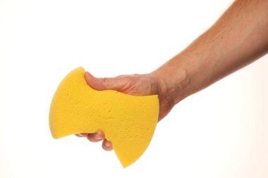 Beyaz arka planda sarı bir sünger tutuyor.