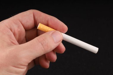 El, arka planda bir sigara tutuyor.