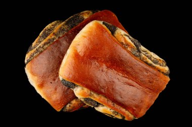 Siyah arka planda haşhaş tohumu ve kekleri olan çörek.