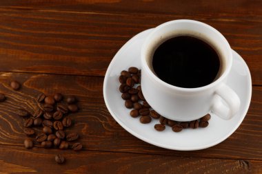 Kahve ve fasulye bir fincanda, tahta bir arka planda.