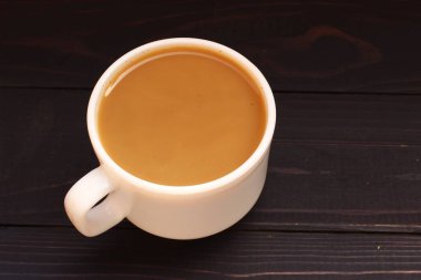 Koyu arkaplanda sütlü bir fincan kahve