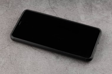 Akıllı telefon kapalı. Masanın üzerinde siyah bir ekran var.