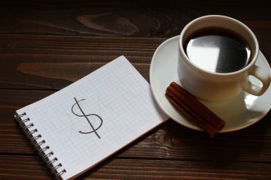 Dolar işareti ve bir not defterine bir fincan kahvenin yanında bir kelime.