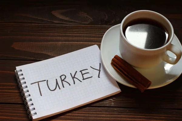 Turkey inscription and word in a notebook near a cup of coffee