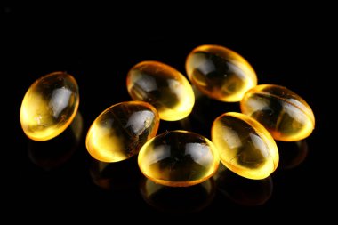 Kapsüllerdeki balık yağı siyah bir arkaplanda.