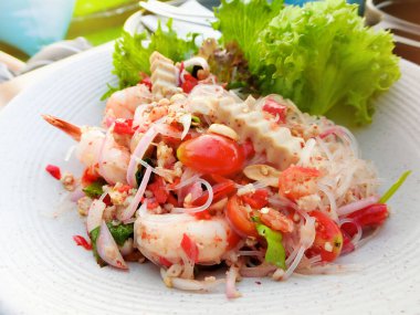 Baharatlı Deniz Ürünleri Salatası 'nı beyaz tabakta sebzeyle karıştır.