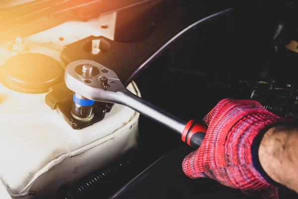 汽车修理厂汽车修理工手拿着红色手套 用插座扳手修理汽车发动机 — 图库照片