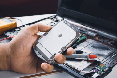 Sabit disk, bilgisayar dizüstü bilgisayarı ve çoklu-metre sonda arkaplanı ile mekanik eli 2,5 inç (HDD) tutuyor