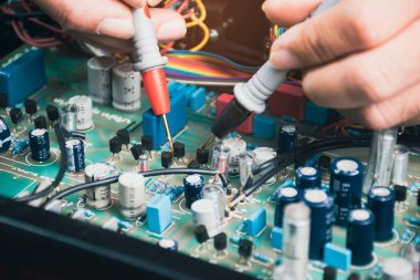 Elektrikçi elektronik devre kartındaki voltajı dijital çoklu metre sondayla kontrol ediyor.