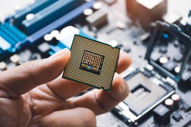 İşlemci çipi teknisyen eli ve bilgisayar anakart arka planında