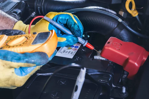 Technician checking DC voltage stable of the car battery with digital multimeter probe