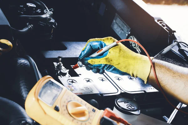 Technician to checking voltage stable of the car battery with digital multimeter probe