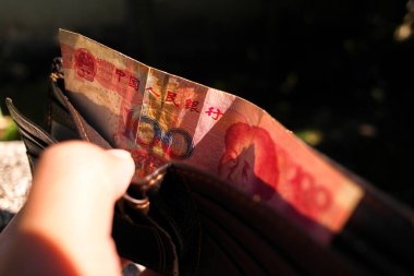 Çin Yuan nakit ödemesi, bir el deri bir cüzdandan 100 Yuan 'lık kırmızı bir banknot çıkardı, nakit işlemleri, Çin ekonomisi ve kişisel harcamalar temsil ediyordu..