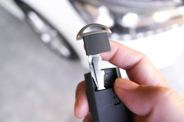 Acil durum anahtarı kaldırma, bir el modern akıllı anahtarlıktan gizli acil durum mekanik anahtarını çıkarır, araç erişimi için hayati bir yedekleme..