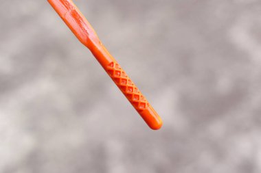 Motor yağı dipstick kontrolü, turuncu plastik motor yağ çubuğunun yakın çekimi, sağlıklı bir sıvı seviyesine işaret eden kehribar motor yağı tabakası gösteriyor..