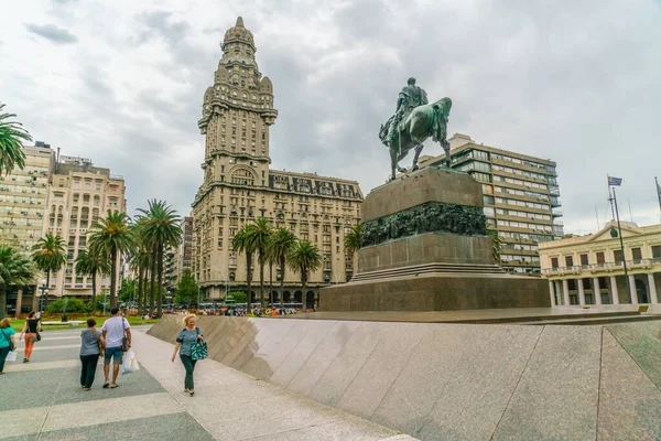 Arkasında ünlü Salvo Sarayı (Palacio Salvo), Montevideo, Uruguay, 25 Ocak 2019 tarihli Bağımsızlık Meydanı 'nda General Artigas' ın (Plaza Indepencia) heykelinin önünden geçen turistler görülüyor.