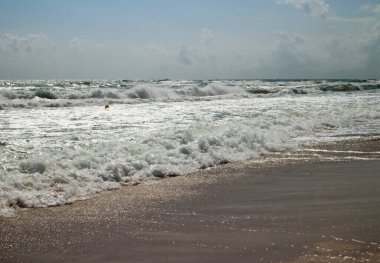 Karadeniz kıyısında deniz, kum ve gökyüzü. Bulgaristan 'ın Primorsko kentinde Karadeniz kıyısında deniz dalgaları.