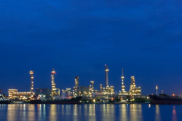 Refinería de petróleo junto a un río durante el crepúsculo —  Fotos de Stock