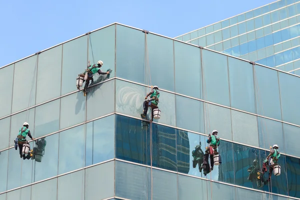 Grupo de trabalhadores serviço de limpeza de janelas em edifício alto — Fotografia de Stock