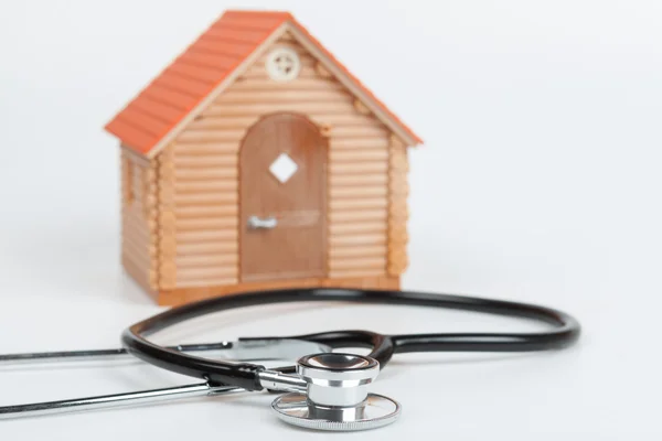 Estetoscópio e casa modelo sobre fundo branco — Fotografia de Stock