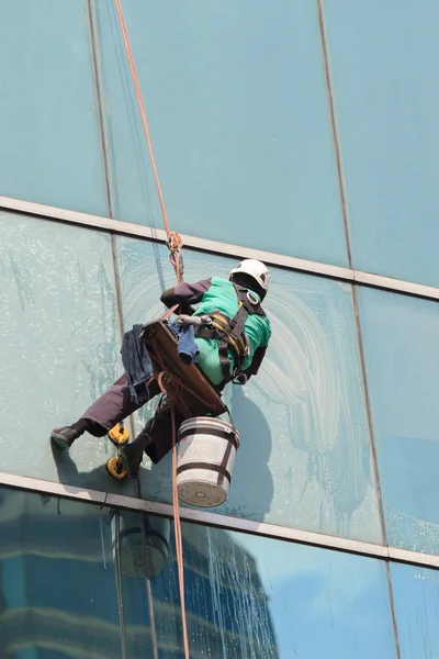 Ein Arbeiter reinigt Fenster an einem Hochhaus — Stockfoto