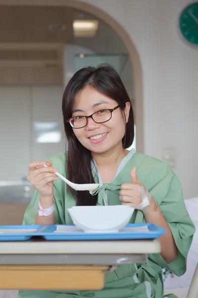 Asiatisk tjej patienten njuter måltid i sjukhussäng — Stockfoto