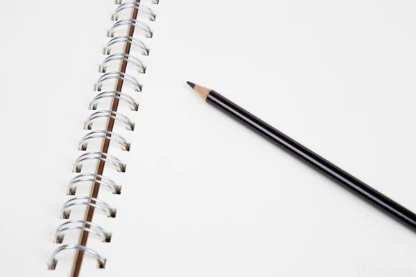 Černá tužka na prázdné notebook — Stock fotografie