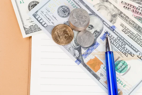 US coins and banknotes with pen on a notebook — Stock Photo, Image