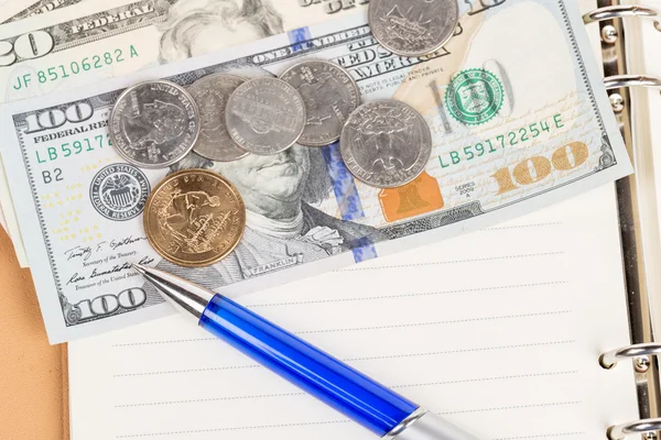 US coins and banknotes with pen on a notebook — Stock Photo, Image