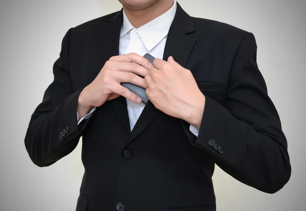 Hombre de negocios guapo metiéndose en el bolsillo de su abrigo para conseguir su billetera . Fotos de stock libres de derechos