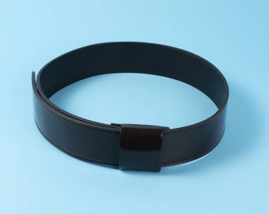 Mavi arka planda siyah deri kemer. Asgari moda kavramı.