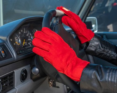 Deri eldivenli kadın ellerini direksiyona koydu. Kış modası geçmişi.
