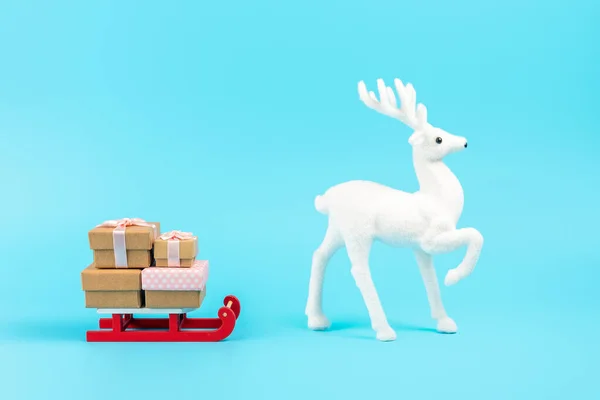 圣诞爪雪橇 礼物盒和蓝色背景的白色驯鹿 最少新年概念 — 图库照片