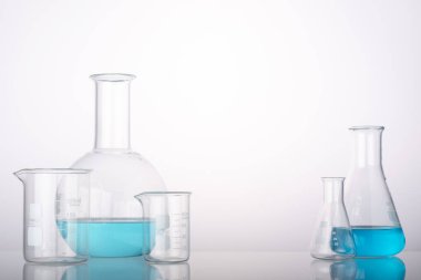 Science and medical background with laboratory glass chemical containers on glass table. Space for products presentation.