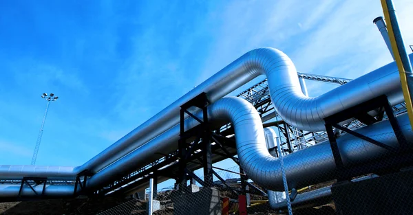 Zona industrial, tuberías de acero y válvulas contra el cielo azul — Foto de Stock